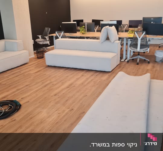 חדר עם ספות, שולחנות עבודה וציוד ניקוי על הרצפה